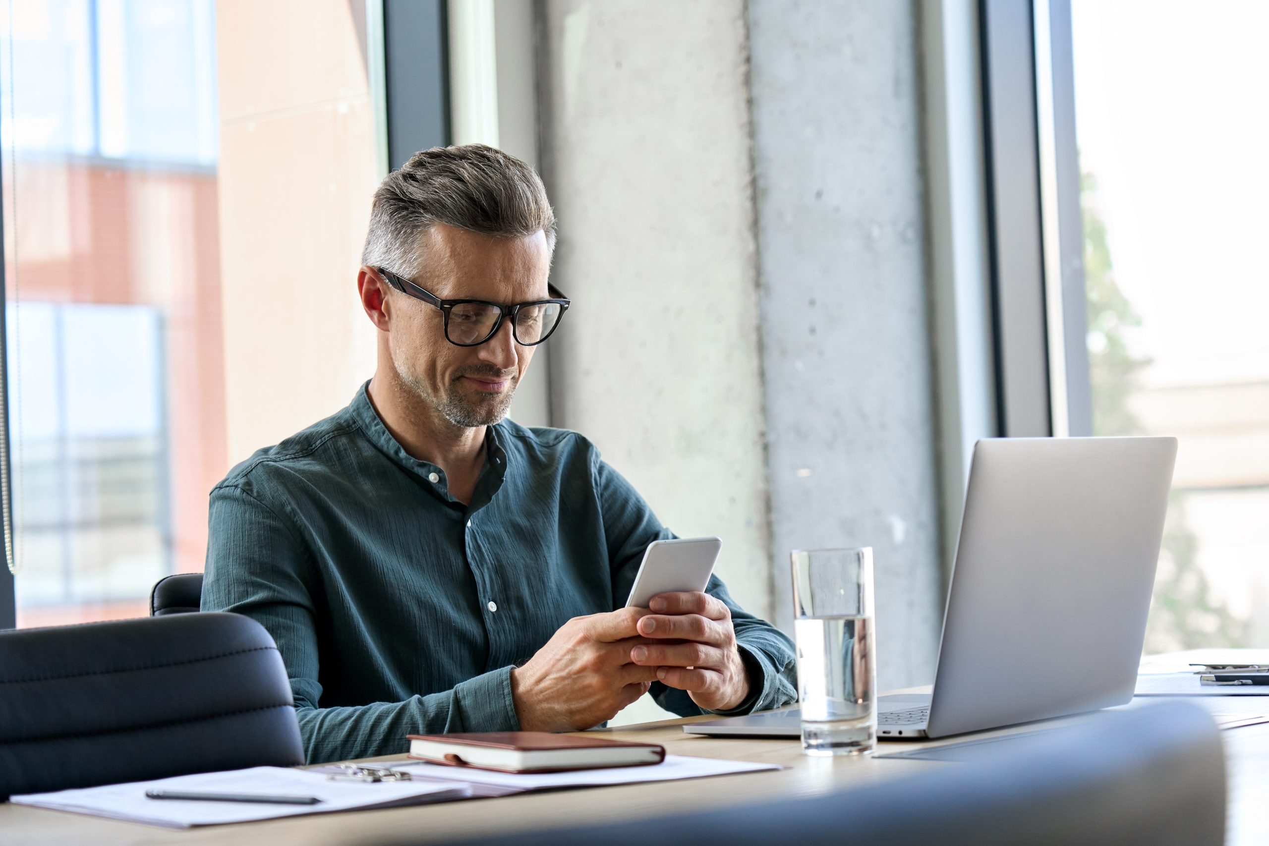 Smiling,Mature,Businessman,Holding,Smartphone,Sitting,In,Office.,Middle,Aged